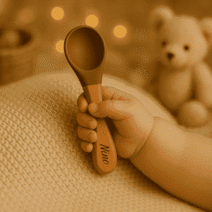 Cuillère bébé personnalisée avec prénom Nino, manche en bois et embout silicone marron, tenue dans la main d’un bébé, accessoire parfait pour les premiers repas. cadeau naissance, baptême, baby shower, anniversaire