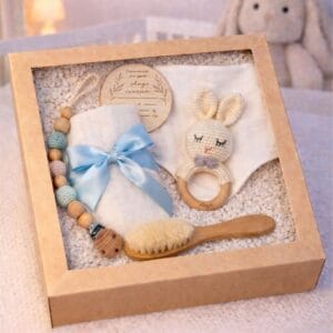 Coffret naissance personnalisé avec hochet lapin en crochet, lange blanc, bavoir, attache tétine, brosse bébé en bois et carte de naissance gravée.