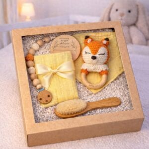 Coffret naissance personnalisé avec prénom bébé comprenant hochet, brosse en bois, lange, bavoir, attache tétine et carte souvenir.